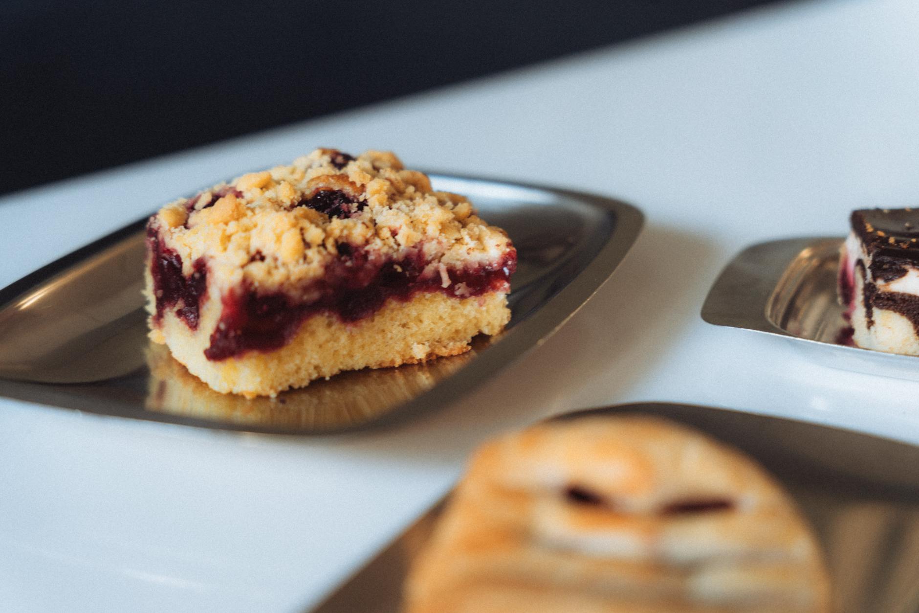 Kawałek drożdżowego ciasta z kruszonką i owocowym nadzieniem na talerzu