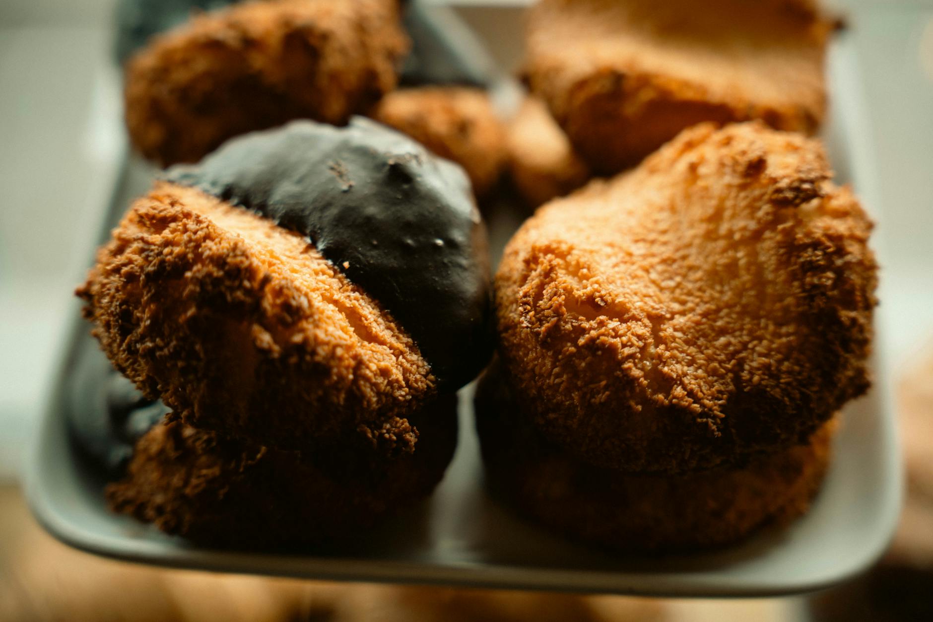 Kokosanki bez mąki: chrupiące na zewnątrz, miękkie w środku Kokosanki bez mąki na talerzu, część zanurzona w czekoladzie