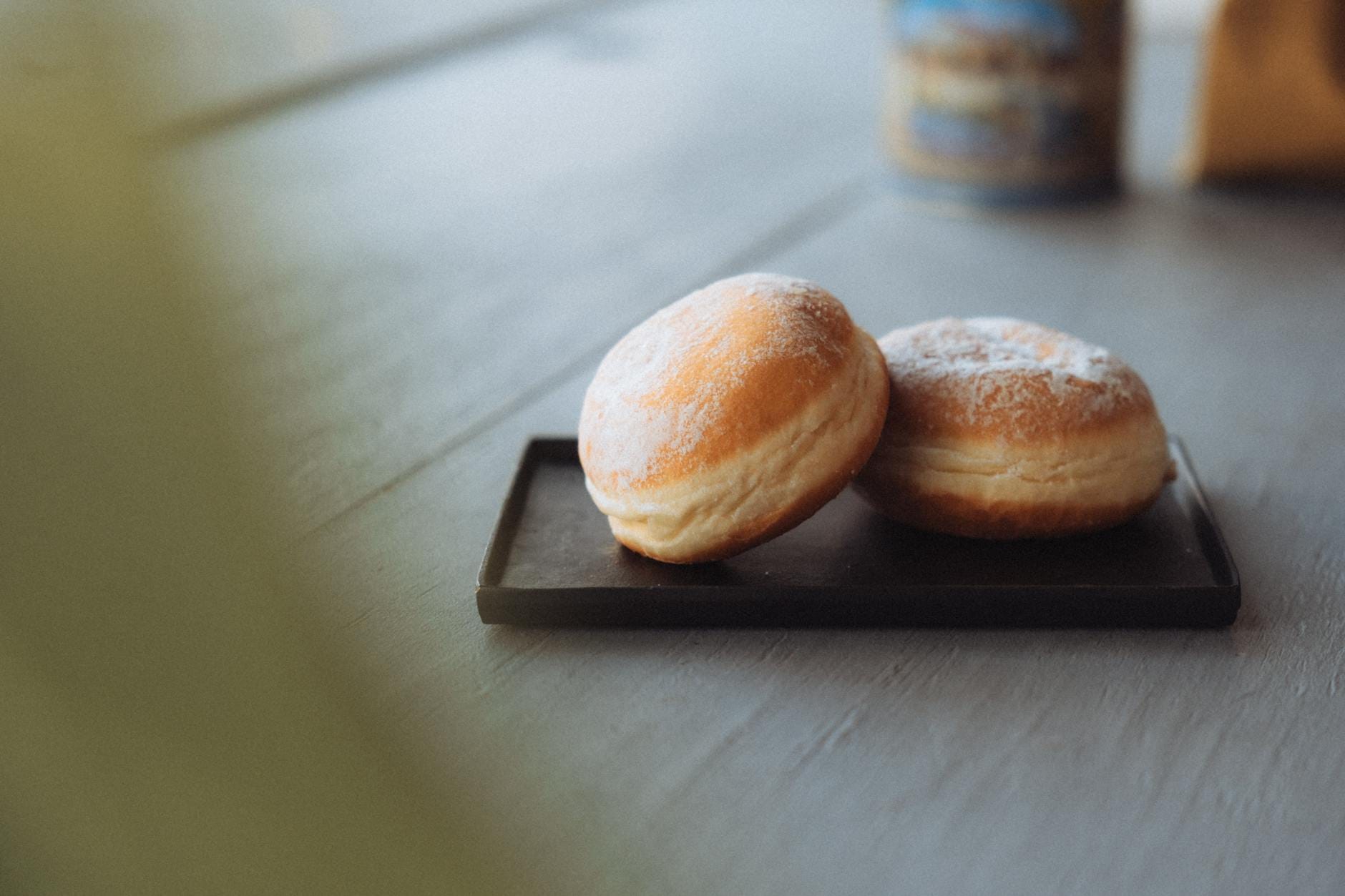Dwa pączki z powidłami śliwkowymi, oprószone cukrem, na tacy