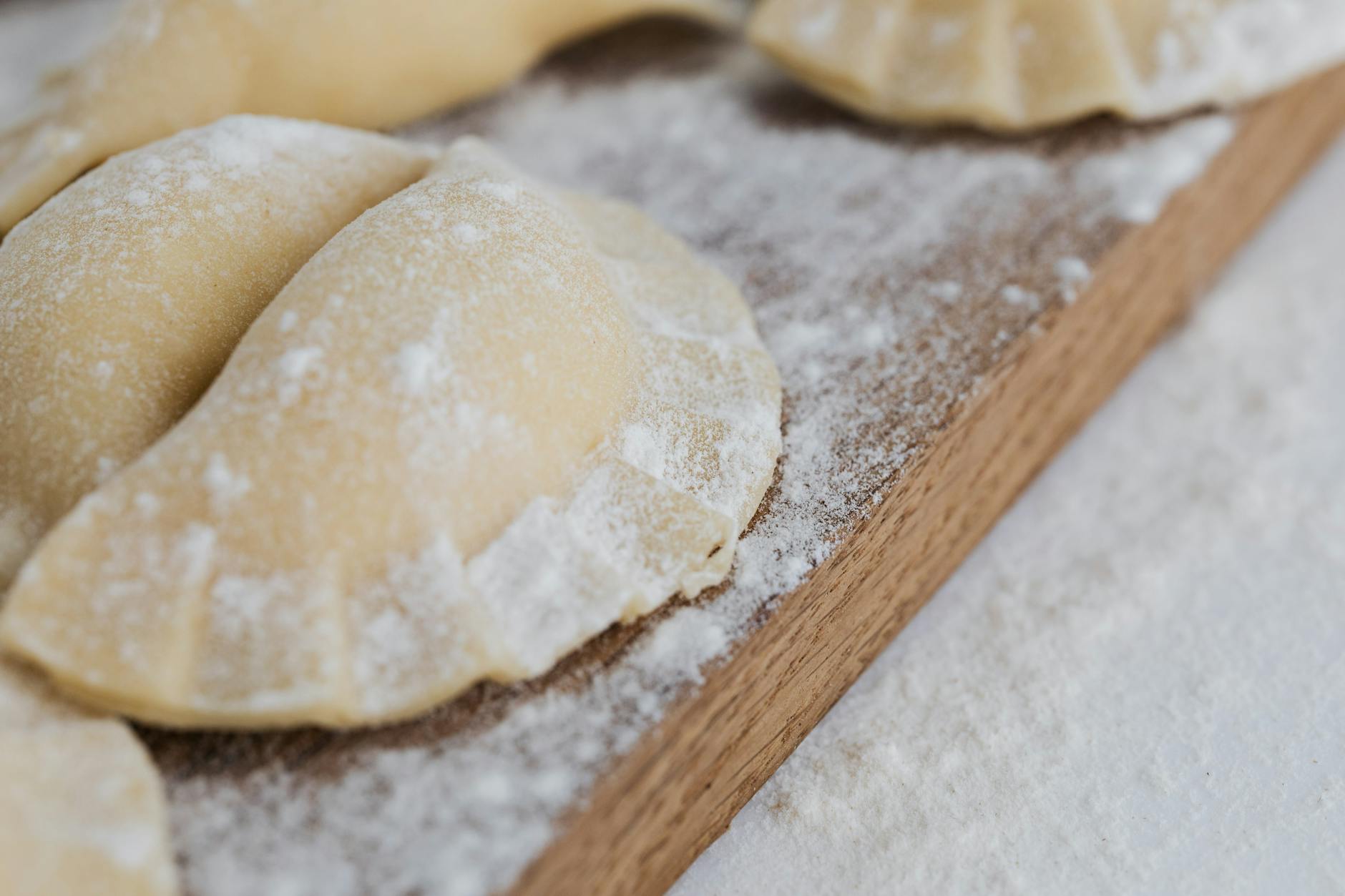 Pierogi na drewnianej desce oprószone mąką, tradycyjna kuchnia polska