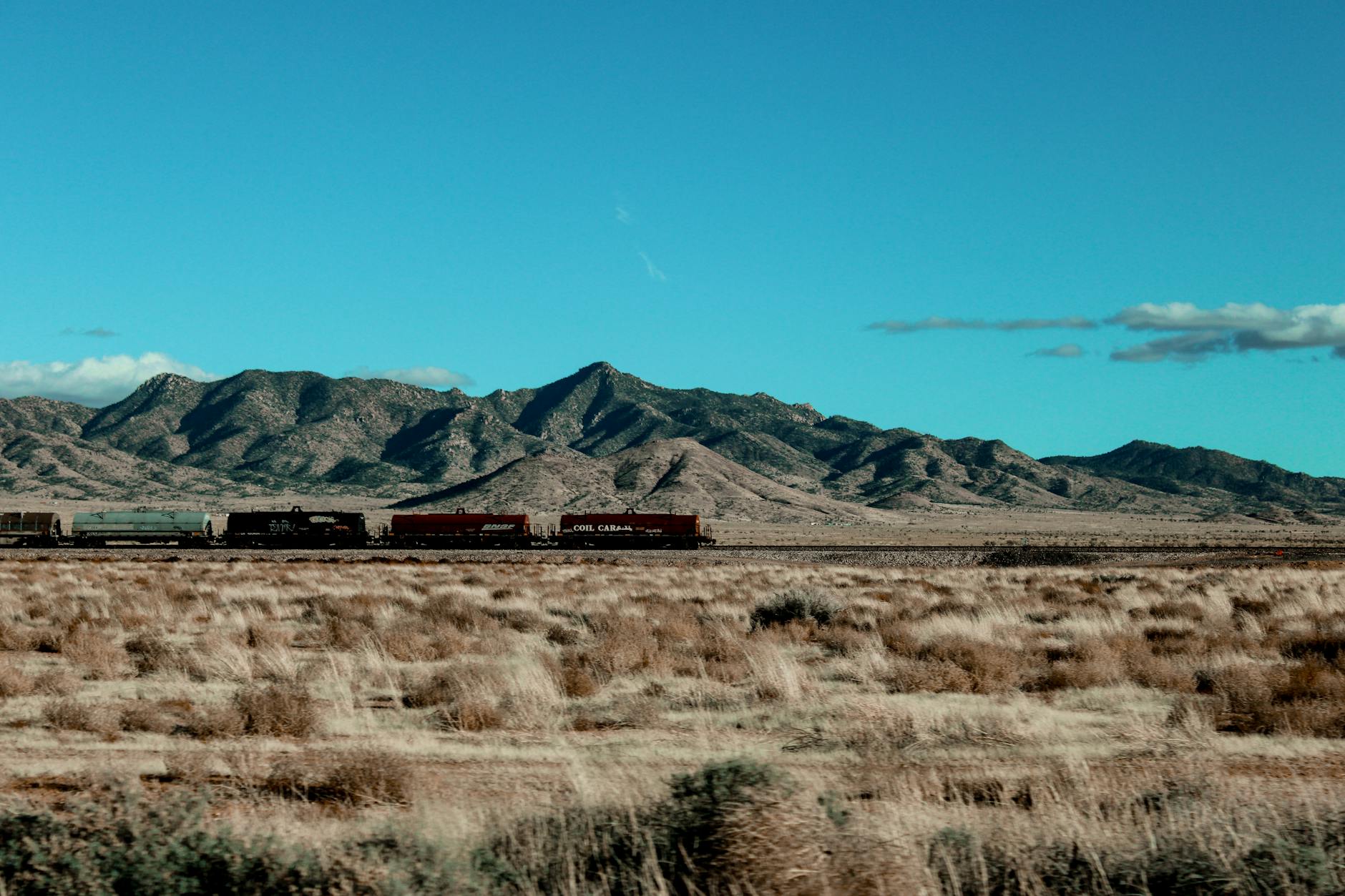 Pociąg jedzie przez pustynne równiny z górami w tle
