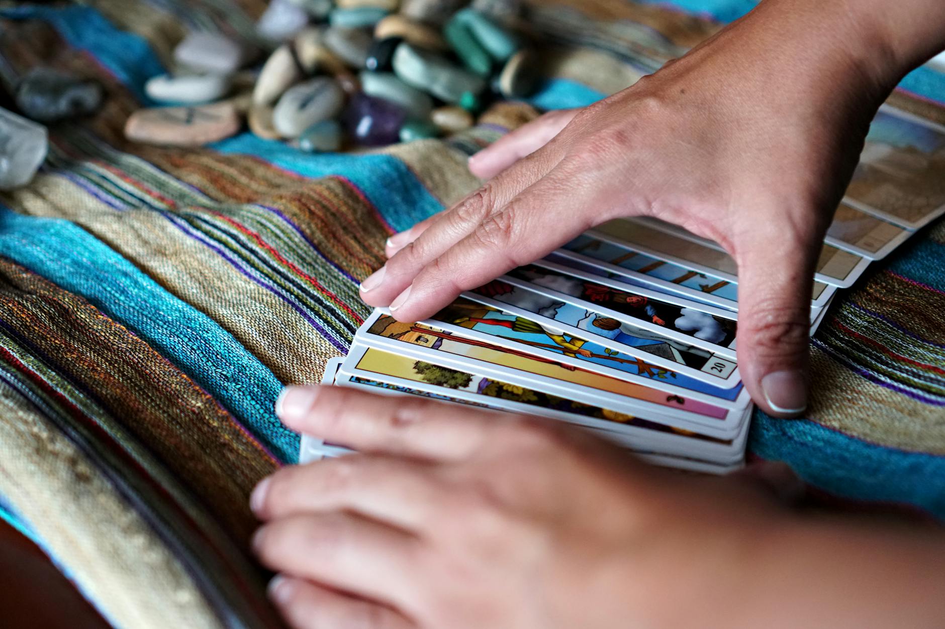 Dłonie rozkładające karty na kolorowej tkaninie z kryształami