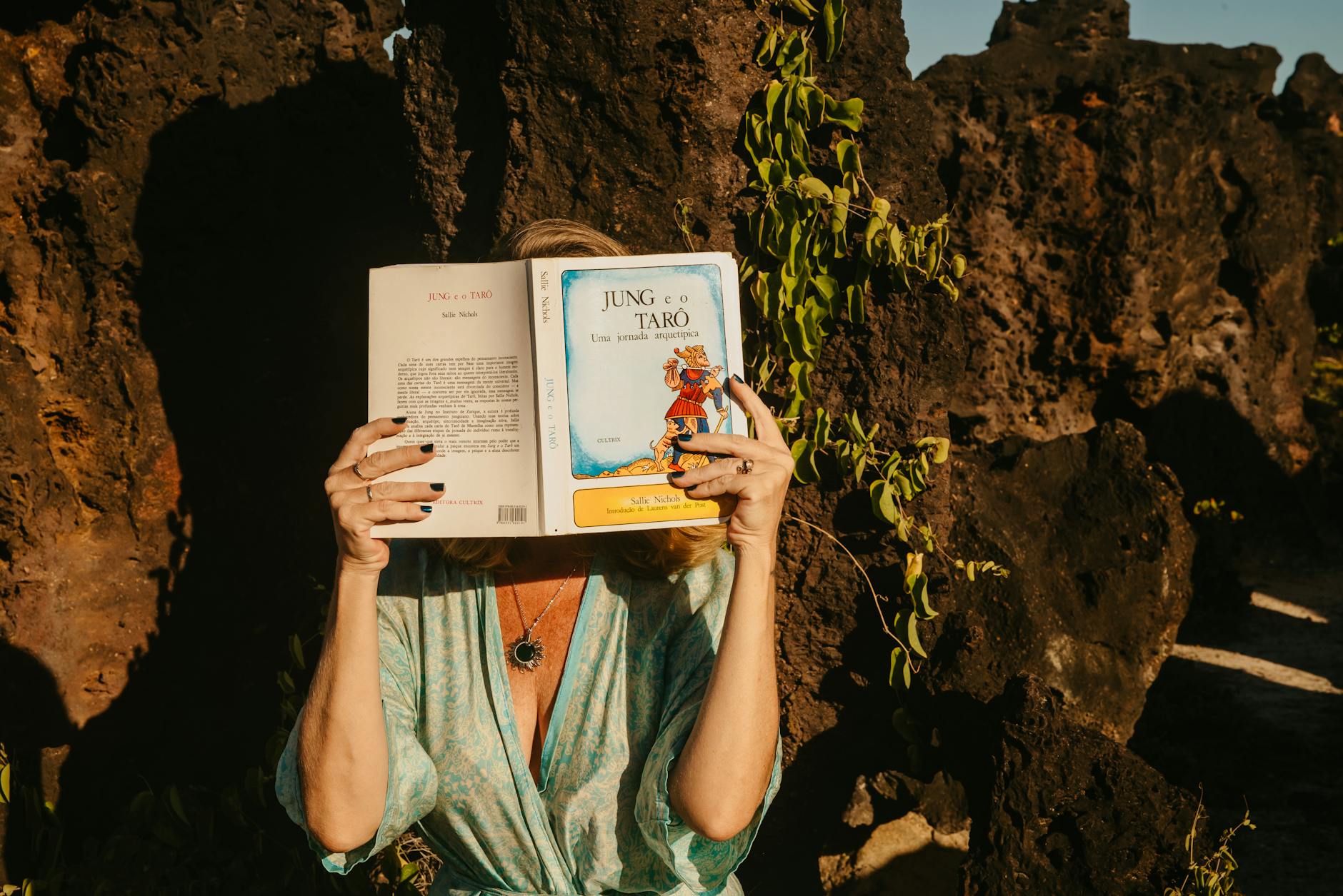 Kobieta czyta książkę Jung and Tarot na skałach w plenerze