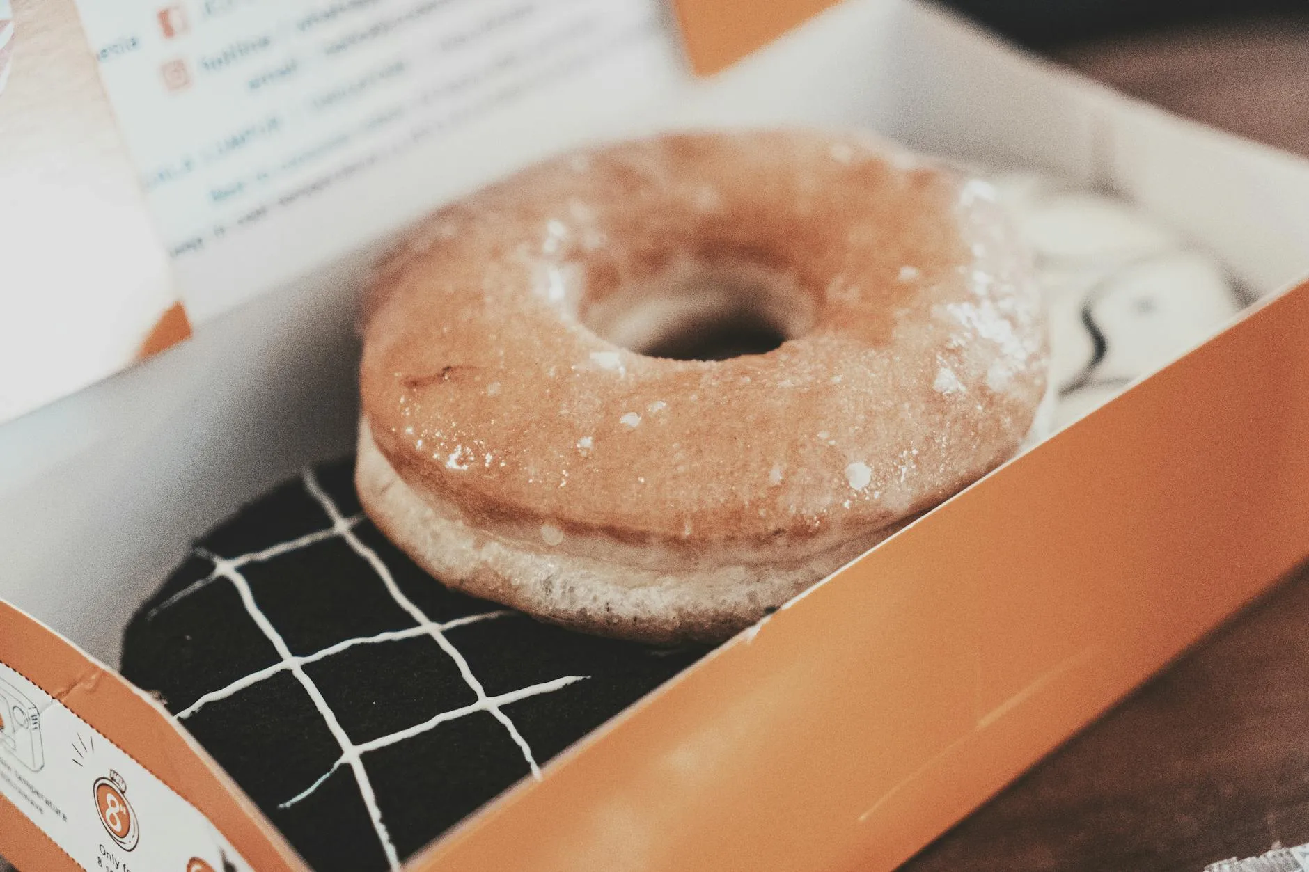 Pączek z gładkim, błyszczącym lukrem w pudełku