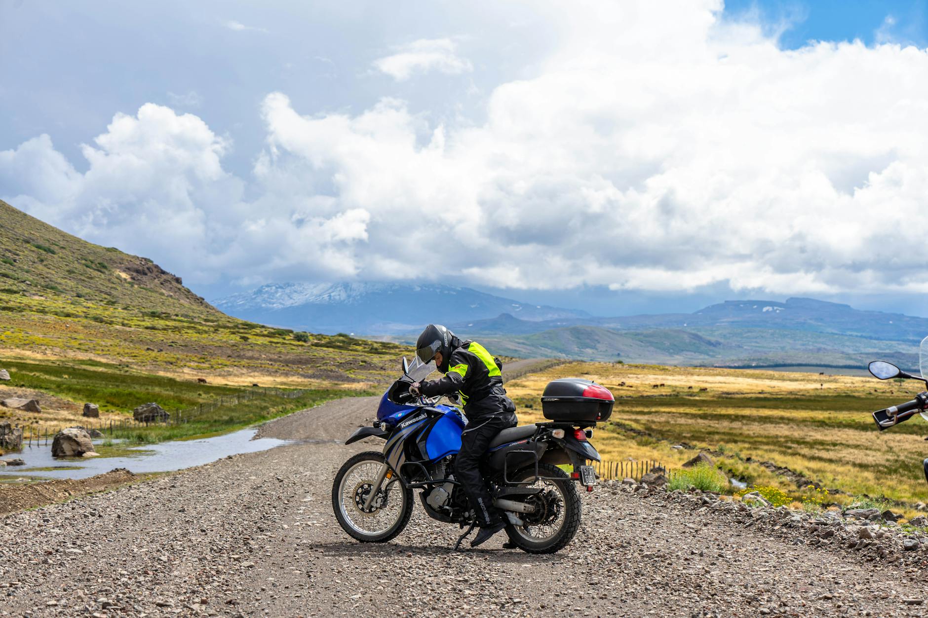 Motocyklista podróżuje po górzystym krajobrazie Argentyny pod chmurami
