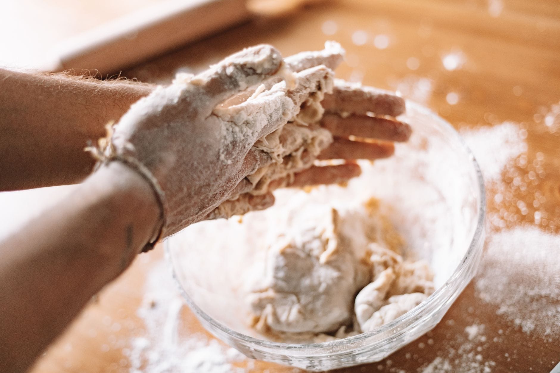 Dłonie zagniatające ciasto drożdżowe na kuchennym blacie