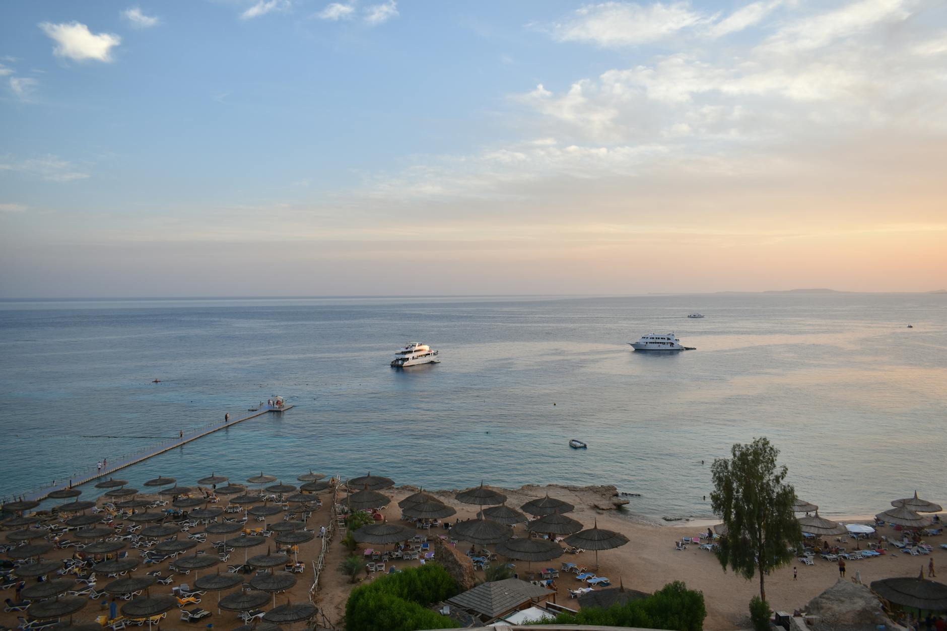 Plaża w Sharm El Sheikh z parasolami i łodziami o zachodzie słońca