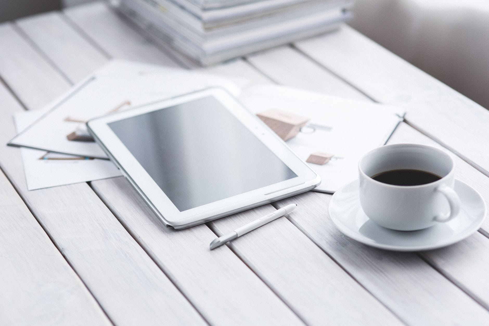 Tablet ze stylusem i kubkiem kawy na minimalistycznym biurku w biurze
